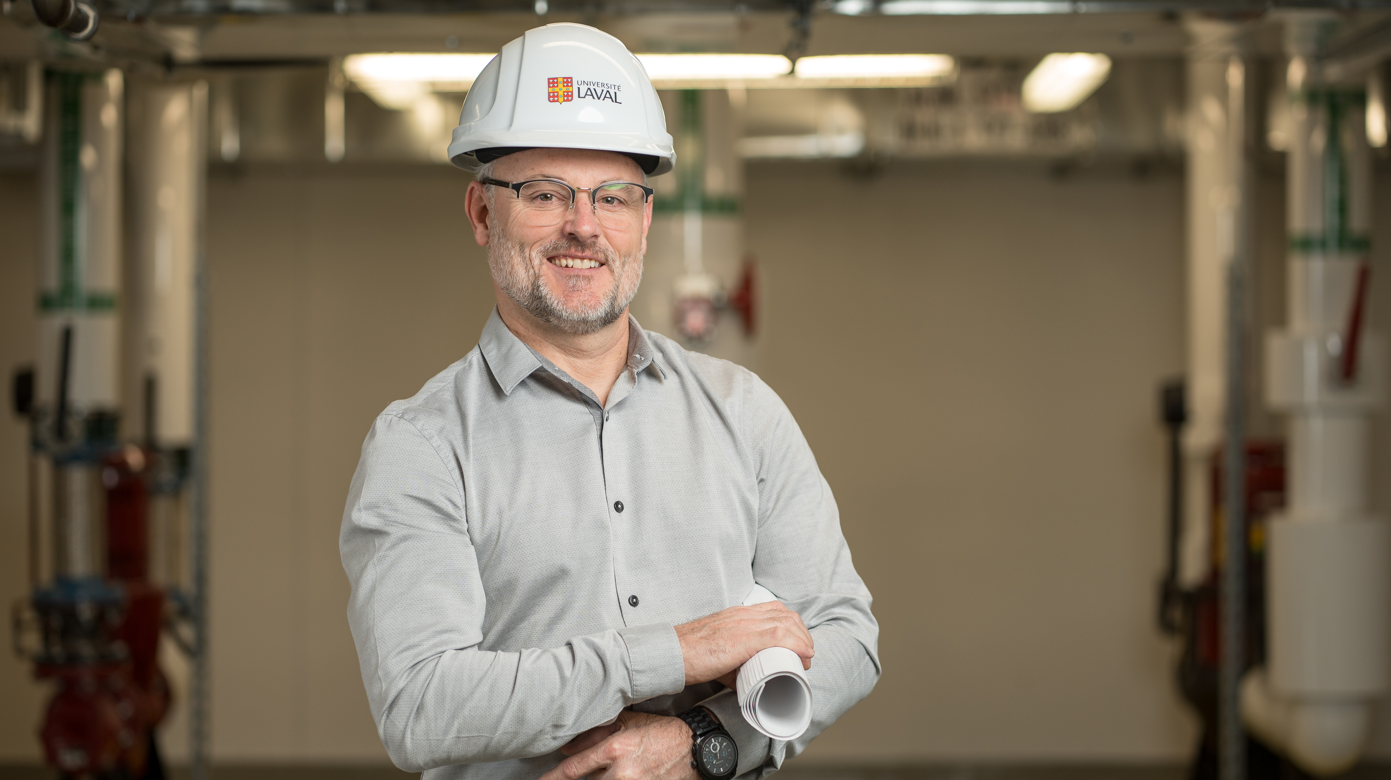 Un ingénieur avec un plan dans les mains et un casque blanc sur la tête