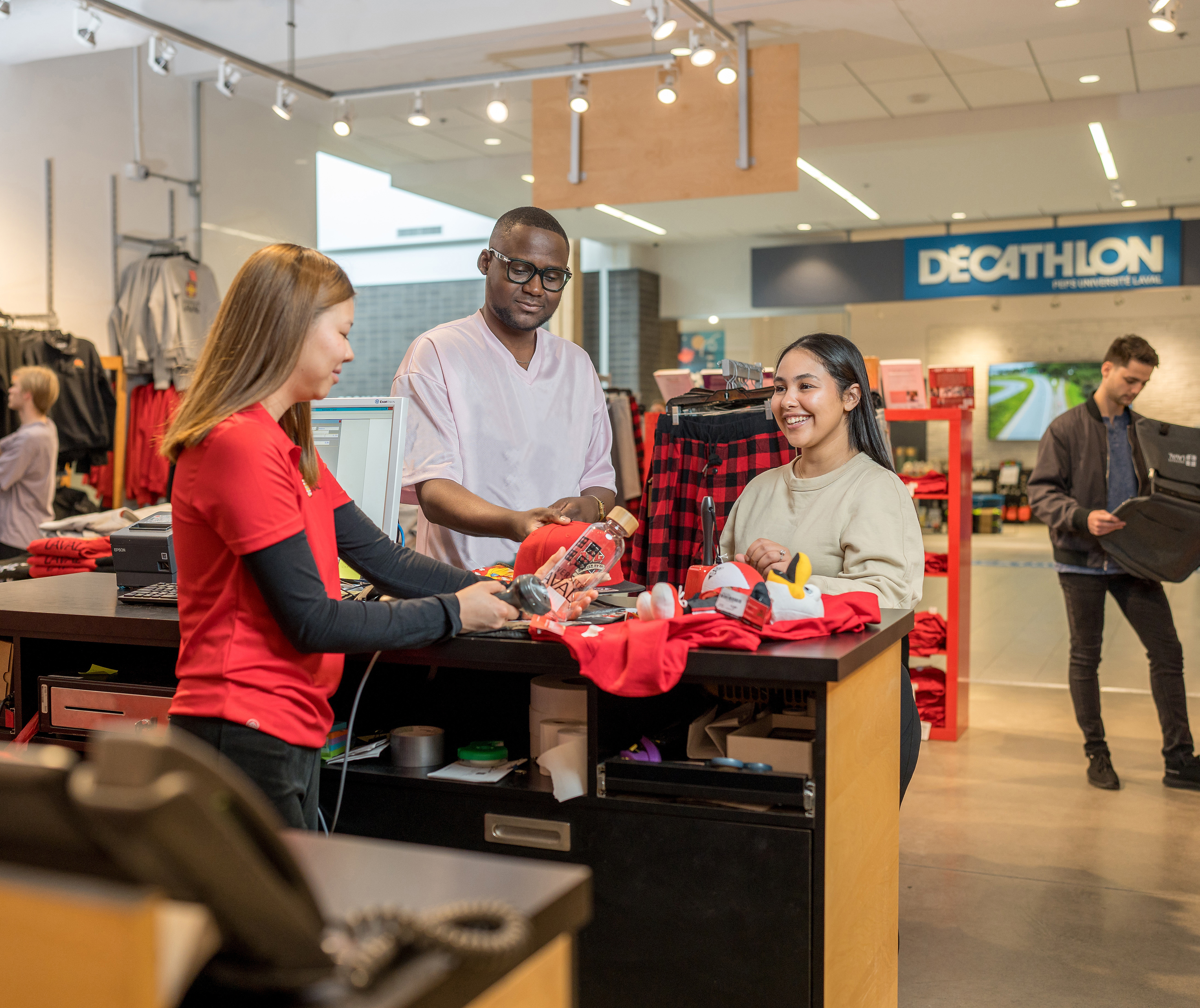 Personnes qui achètent des articles aux couleurs de l'Université Laval dans une boutique sur le campus